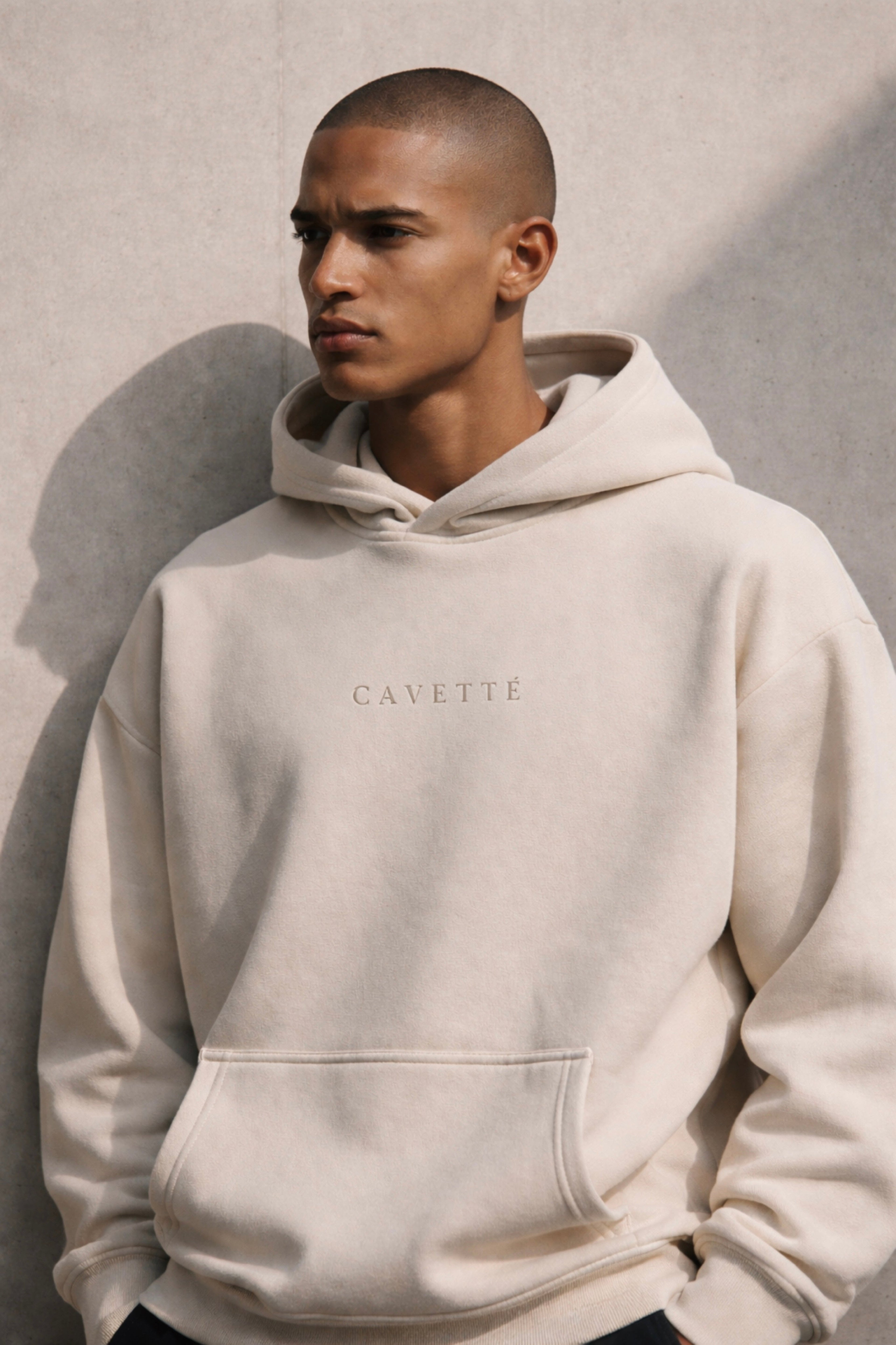 Man wearing a beige hoodie with 'Cavette' branding against a neutral background